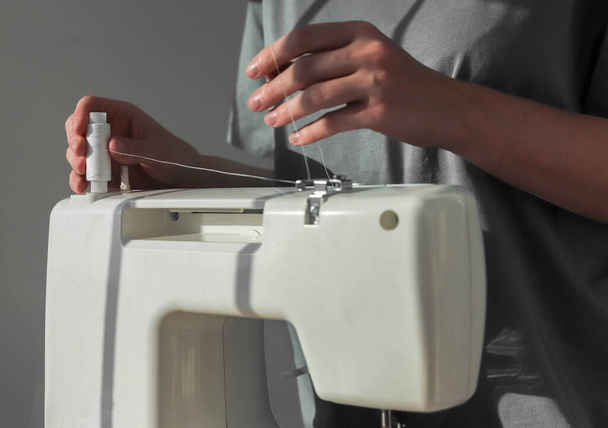 Seamstress hands putting thread spool on sewing machine - Fotoğraf, Görsel