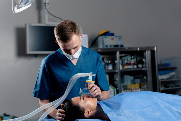 Anestezjolog przygotowujący znieczulenie ingalacyjne dla pacjenta. Lekarz zakłada maskę pacjentowi przed rozpoczęciem operacji.. - Zdjęcie, obraz
