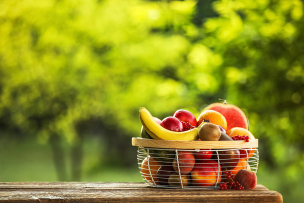 Basket with fresh fruits on table outdoors - 写真・画像