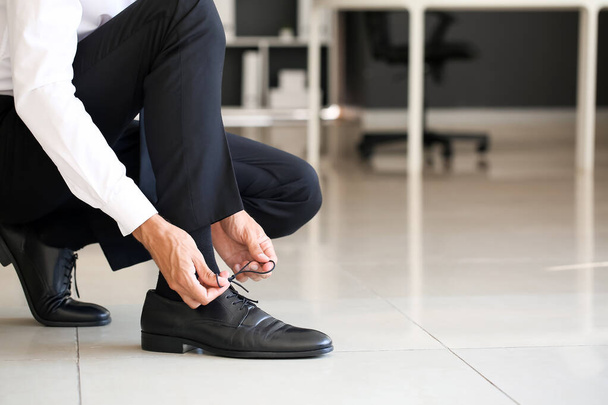 Empresário amarrando cadarços de sapatos no escritório - Foto, Imagem