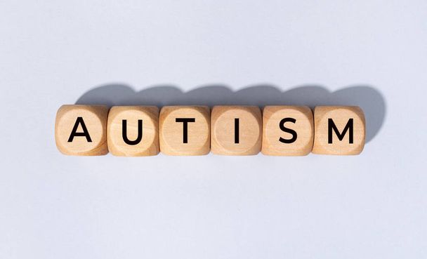 Autism word on wooden block isolated on gray background - Foto, imagen