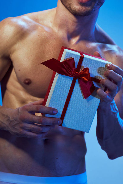 sporty man with a pumped-up torso with a gift in his hands holiday - Photo, Image