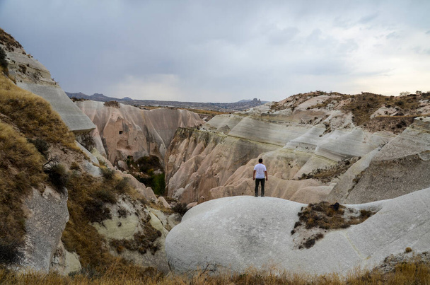 Чоловік стоїть біля чудових каменів і захоплюється вулканічним ландшафтом Каппадокії, що в Туреччині. Подорож, свобода, досягнення. - Фото, зображення
