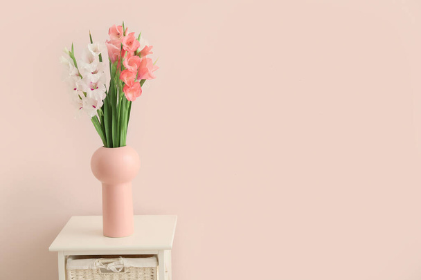 Vase with gladiolus flowers on table in room - Foto, imagen