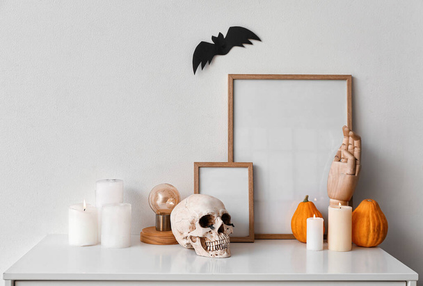 Blank frames with Halloween decorations on shelf near light wall - Fotó, kép