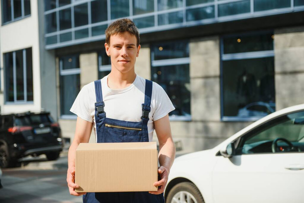 Smiling delivery man holding a paper box - Photo, image