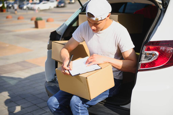 Young Delivery Man Checking List On Clipboard In car - Foto, immagini