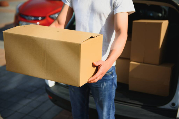 Deliveryman holds parcels at the car, delivering - Fotó, kép