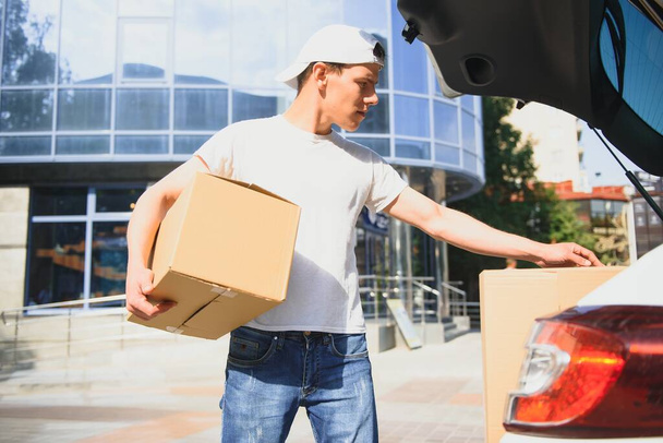 Deliveryman holds parcels at the car, delivering - Photo, image