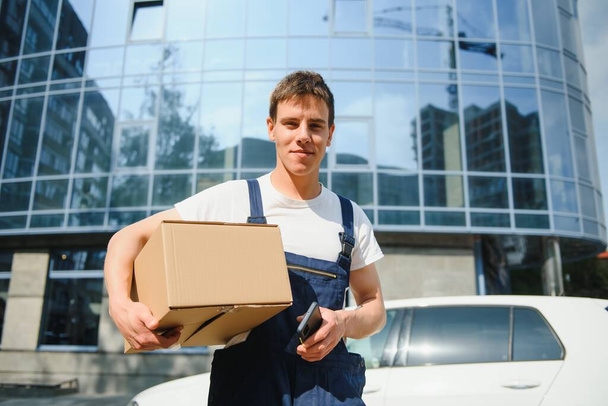 Smiling delivery man standing in front of his car - Foto, imagen