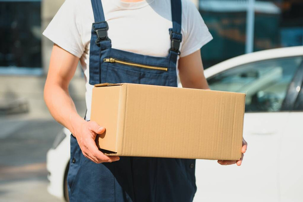 A man carrying package from delivery car - courier service concept - Foto, Bild
