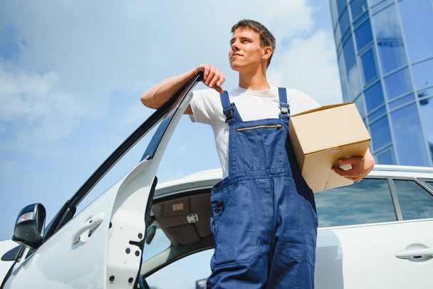 Deliveryman holds parcels at the car, delivering - Fotoğraf, Görsel