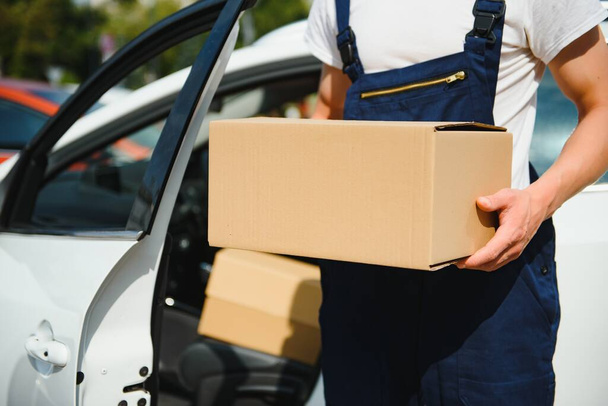 Deliveryman holds parcels at the car, delivering - Foto, immagini