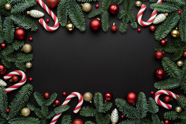 Moldura de ornamentos de Natal com ramos de abeto em um fundo preto. Flat lay, vista superior e espaço de cópia para texto - Foto, Imagem