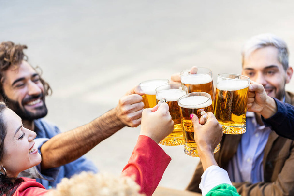 Gruppo di amici felici multirazziali tifo con birre al bar della birreria terrazza - Foto, immagini