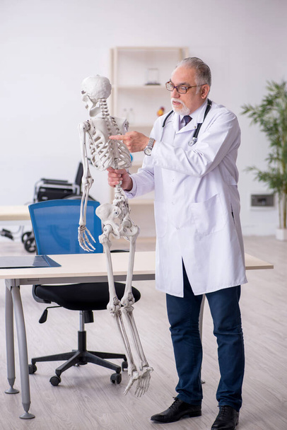 Old male doctor demonstrating human skeleton - Foto, imagen