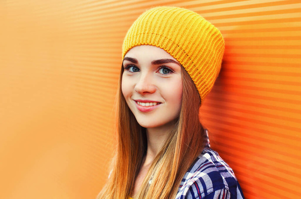 Pretty blonde woman wearing a yellow hat on city street over orange wall background - Fotoğraf, Görsel