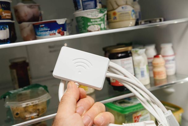 Otwarte drzwi lodówki z męską ręką trzymającą nowy klucz Wi-Fi do nowoczesnych lodówek - Zdjęcie, obraz
