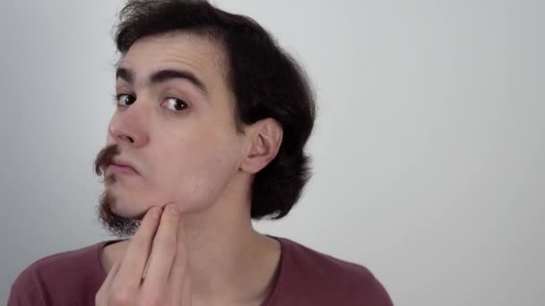 Porträt eines Mannes, der einen rasierten Teil seines Gesichts mit dem bärtigen vergleicht - Filmmaterial, Video