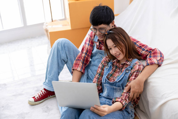 Yom-bearドレスとplidsシャツの恋人カップルが新しい家のコンセプトでノートPCの若いカップルで新しい家のペイントの色を選択して座っている - 写真・画像