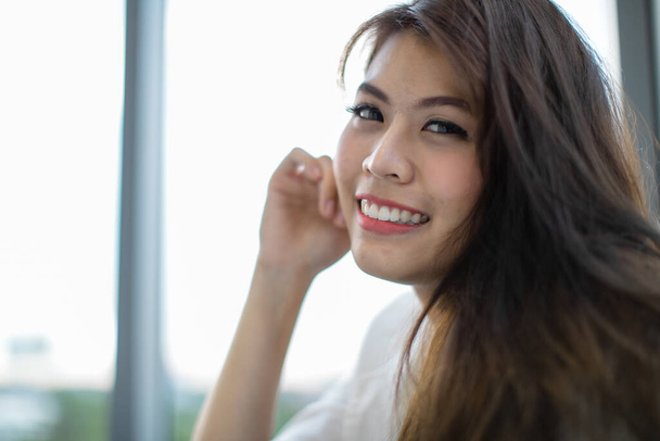 Giovane bella donna asiatica felice sorridente e giocoso emozione, rilassante sul divano, sfondo sfocato per spazio copia. - Foto, immagini