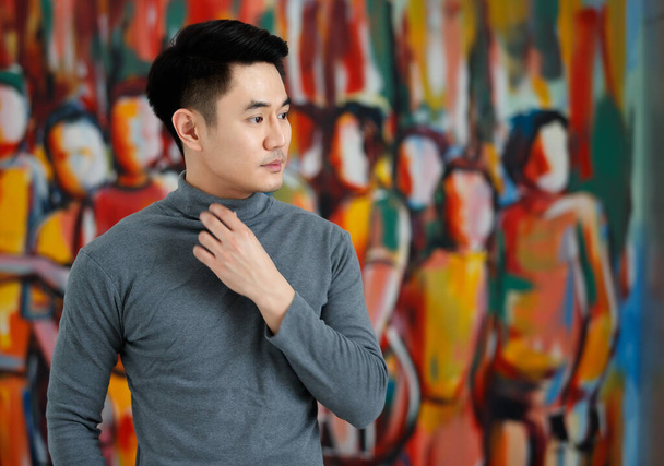 Portrét fo asijský muž pohledný usmívající se pryč nosí šedý dlouhý rukáv tričko stojící na uměleckém obrázku pozadí - Fotografie, Obrázek