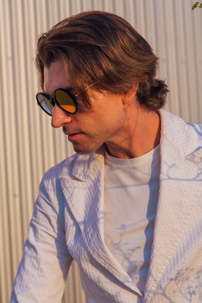 Close up portrait of a handsome man with round hippie sunglasses during sunset - Foto, Imagem