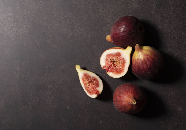 Lots of figs and cut figs on a dark background. View from above. - Fotografie, Obrázek