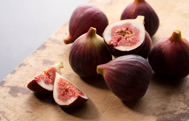 Paljon viikunoita leikkuulaudalla ja leikkaa figs.Image viikunoita. - Valokuva, kuva