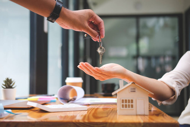 Агент по недвижимости дает ключи новым владельцам недвижимости после подписания договора аренды или договора купли-продажи. - Фото, изображение