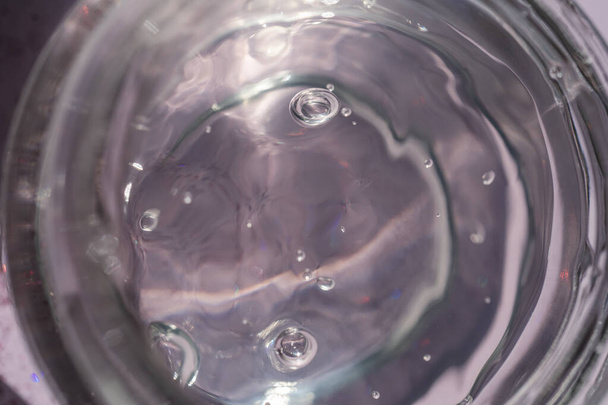 Transparent gel in a jar on a lilac background. - Φωτογραφία, εικόνα