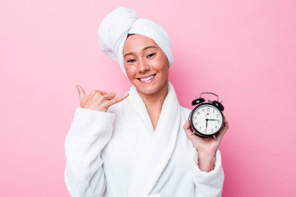 Young australian woman leaving the shower late isolated on pink background showing a mobile phone call gesture with fingers. - Foto, imagen