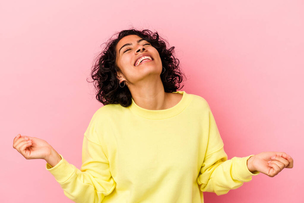 Young curly latin woman isolated on pink background relaxed and happy laughing, neck stretched showing teeth. - Photo, Image