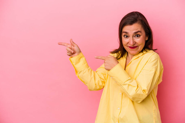 Middle age caucasian woman isolated on pink background pointing with forefingers to a copy space, expressing excitement and desire. - Photo, Image