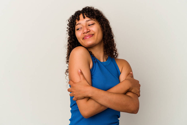 Young mixed race woman isolated on white background hugs, smiling carefree and happy. - Photo, Image