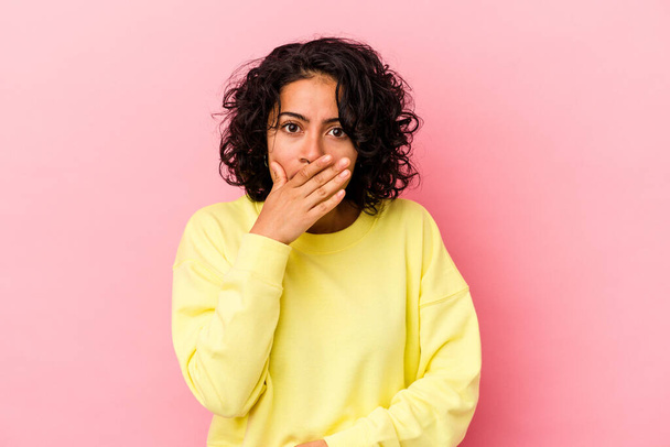 Young curly latin woman isolated on pink background covering mouth with hands looking worried. - Fotografie, Obrázek