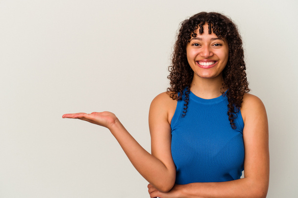 Young mixed race woman isolated on white background showing a copy space on a palm and holding another hand on waist. - Foto, Imagen