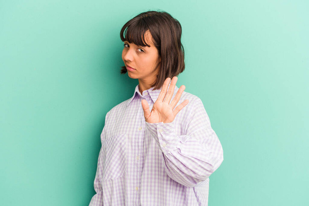 Young mixed race woman isolated on blue rejecting someone showing a gesture of disgust. - Photo, Image
