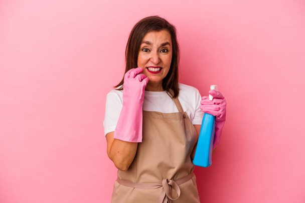 Keski-ikäinen valkoihoinen nainen puhdistaa kotiin eristetty vaaleanpunainen tausta puree kynnet, hermostunut ja hyvin ahdistunut. - Valokuva, kuva
