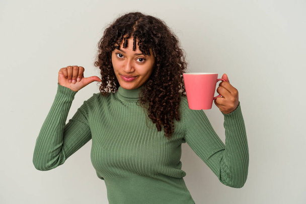 Young mixed race woman holding a mug isolated on white background feels proud and self confident, example to follow. - Fotó, kép