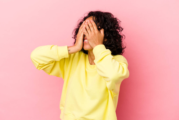 Joven mujer latina rizada aislada sobre fondo rosa miedo cubriendo los ojos con las manos. - Foto, Imagen