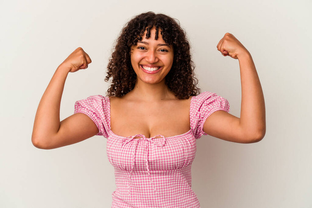 Young mixed race woman isolated on white background showing strength gesture with arms, symbol of feminine power - Fotografie, Obrázek