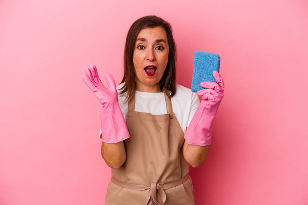 Middle age caucasian woman cleaning home isolated on pink background surprised and shocked. - Foto, Imagen