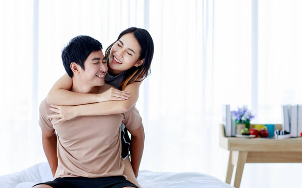 Iloinen etninen poikaystävä ja tyttöystävä halaavat hellästi ja hymyilevät kotona samalla kun he ilmaisevat rakkautta. - Valokuva, kuva
