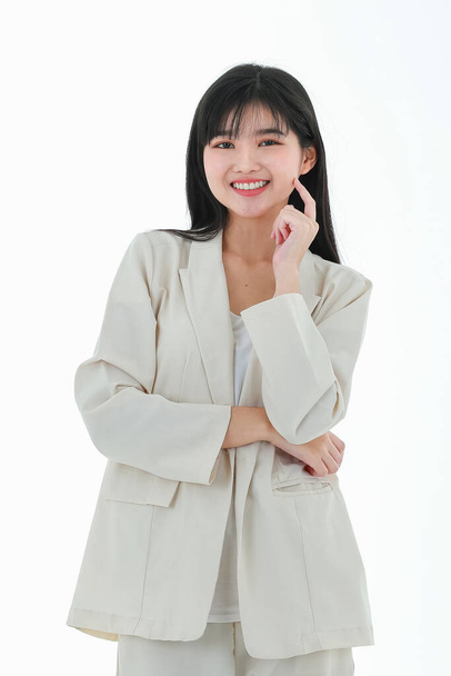 Jeune femme d'affaires asiatique a un grand sourire et pointeur du doigt avec excité, regardant vers le côté sur l'espace de copie fond blanc et en pensant à quelque chose d'excité, de plaisir et de bonheur - Photo, image