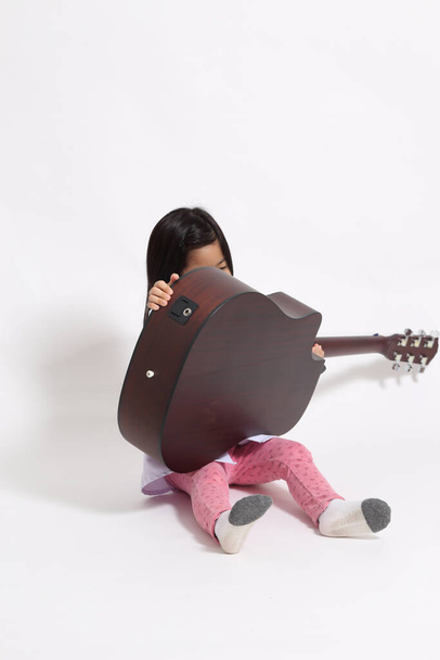 The young Asian girl with acoustic guitar on the whit background. - Fotó, kép
