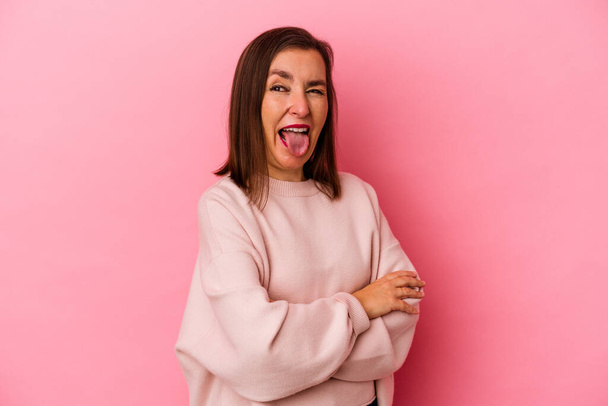 Середньовічна біла жінка ізольована на рожевому тлі смішна і доброзичлива, що стирчить язиком
. - Фото, зображення