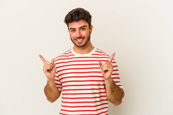Jeune homme caucasien isolé sur fond blanc pointant vers différents espaces de copie, en choisissant l'un d'eux, montrant avec le doigt. - Photo, image