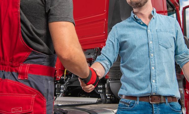 Camionneur et son mécanicien serrant la main devant le tracteur semi-camion moderne. Thème de l'industrie du transport lourd. - Photo, image