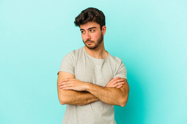 Young caucasian man isolated on blue background dreaming of achieving goals and purposes - Photo, Image